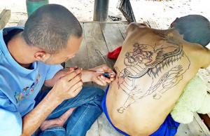 Læremester Sorelae tatoverer en enhjørning fra kinesisk mytologi på en ung mann kalt Em.